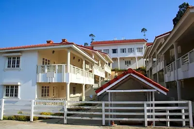 a row of apartment buildings with a white fence at LMS Palve Sugavasam in Ooty