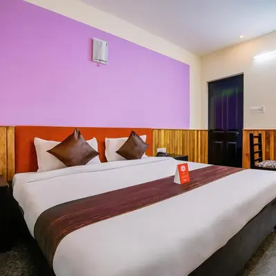 a large bed in a room with a purple wall at LIMRA INN RESIDENCY cottage in Ooty