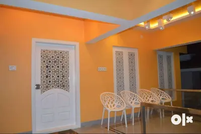 a dining room with orange walls and a white door at Charis Villa and Guest house 5bed 4bath in kunnamkulam in Kunnamkulam
