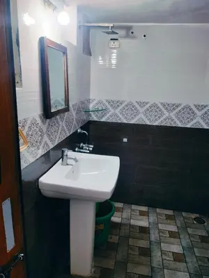 a bathroom with a white sink and a mirror at The Palmyrah Tenements in Mysore
