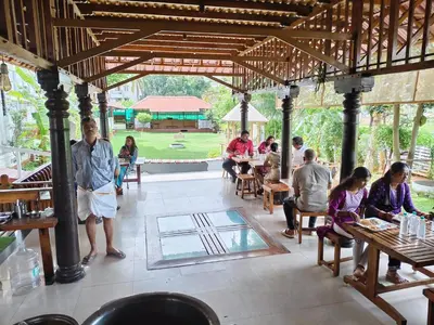a group of people sitting at tables in a restaurant at The Palmyrah Tenements in Mysore