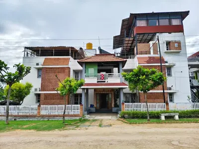 a tall white building with trees in front of it at The Palmyrah Tenements in Mysore