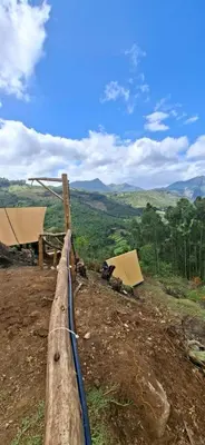 a wooden fence on a hill with a view of a field at Daddy's MAD house in Kottakamboor