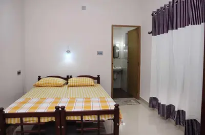 a bedroom with a bed with a yellow and white comforter at legacy beach stay kannur in Kannur