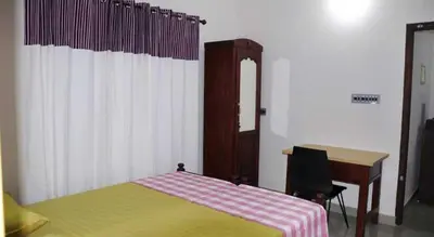 a bedroom with a desk and a bed with a table and a chair at legacy beach stay kannur in Kannur