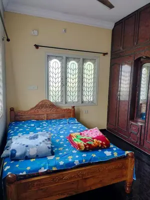 a bedroom with a bed with blue sheets and windows at PG For Men in Mysore