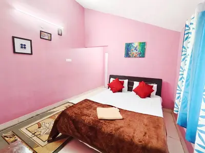 a bedroom with pink walls and a bed with red pillows at Greenland 2bed room hall villa in Ooty