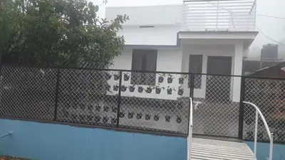 a fence around a swimming pool in front of a house at Couples Nest in Kottakamboor