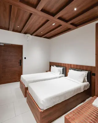 two beds in a room with wooden ceilings at Mayanadhi Resort in Irimbranallūr