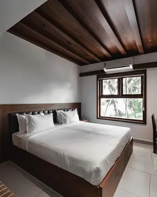 a bedroom with a large bed with a wooden ceiling at Mayanadhi Resort in Irimbranallūr