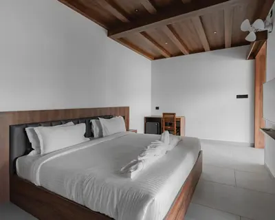 a bedroom with a large bed with white sheets at Mayanadhi Resort in Irimbranallūr