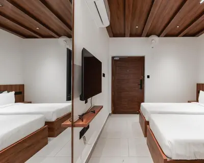 a bedroom with two beds and a tv on the wall at Mayanadhi Resort in Irimbranallūr