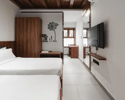 a bedroom with two beds and a flat screen tv at Mayanadhi Resort in Irimbranallūr