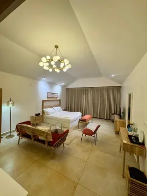 a bedroom with a bed and a table and a chandelier at Feliz by slowlane stays in Kotagiri