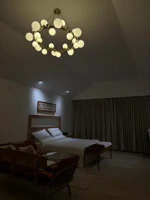 a bedroom with a bed and a chandelier at Feliz by slowlane stays in Kotagiri