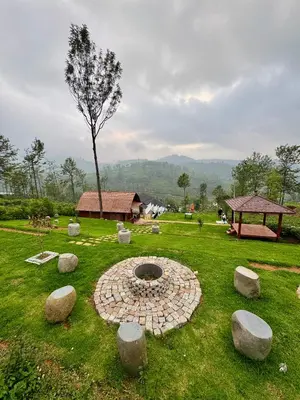 a garden with a fire pit in the grass at Feliz by slowlane stays in Kotagiri