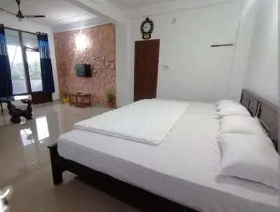 a bedroom with a large white bed with a clock on the wall at Tapovan Fruitopia in Sultan Bathery