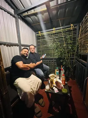 two men sitting on a table in a room at Tapovan Fruitopia in Sultan Bathery