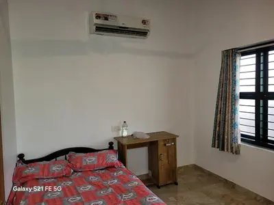 a bedroom with a bed and a table and a window at Home stay in Manjeri