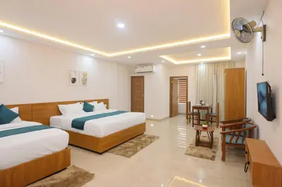 a hotel room with two beds and a table at Munderi Green Mounts - Family Rooms with Swimming Pool in Kalpetta