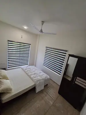 a bedroom with a bed and two windows at Satori Stays - KMA Apartments in Kozhikode