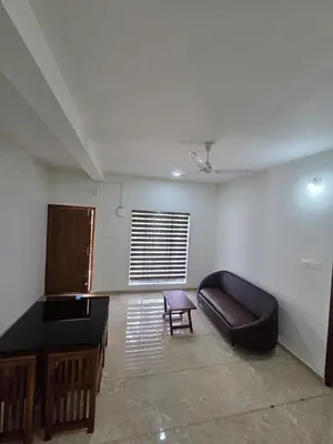 a living room with a couch and a table at Satori Stays - KMA Apartments in Kozhikode
