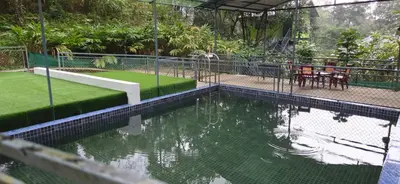 a pool of water with a table and chairs at Hill valley farm resort in Viripara