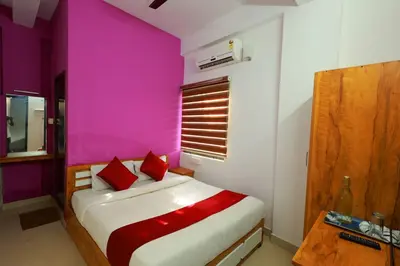 a bedroom with pink walls and a bed with red pillows at Calicut residency in Kozhikode