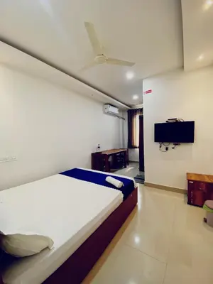 a bedroom with a bed and a flat screen tv at Metro Residency in Perintalmanna