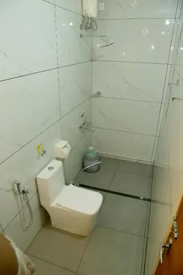 a white bathroom with a toilet and a shower at Cloud9 Airport Hotel in Nedumbassery