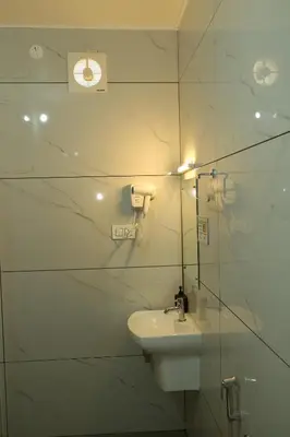 a white bathroom with a sink and a mirror at Cloud9 Airport Hotel in Nedumbassery