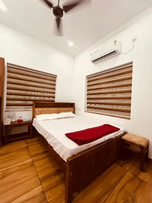 a bedroom with a bed with a red blanket on it at Green Villa Chirackal Gardens in Trichūr