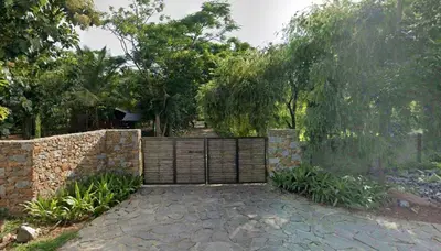 a stone wall with a wooden fence in a yard at Trisara Boutique Stay in Mysore