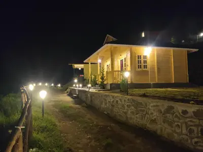 a house with lights on the side of it at night at Cloudy Nandy Hills Poombarai in Kūkkāl