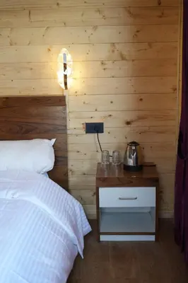a bedroom with a bed and a wooden wall at Cloudy Nandy Hills Poombarai in Kūkkāl