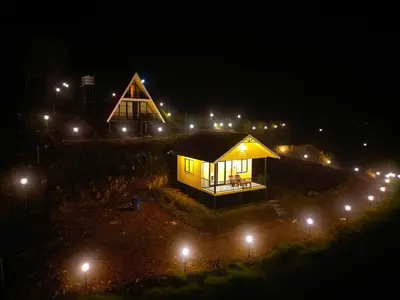 a small building with lights on it at night at Cloudy Nandy Hills Poombarai in Kūkkāl