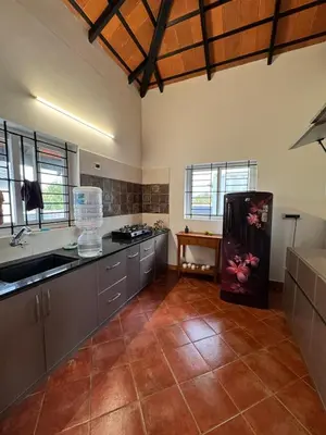 a large kitchen with a sink and a refrigerator at Chettinadu Pool Villa in Pollāchi