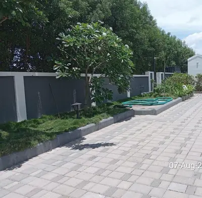 a sidewalk with a tree and green hose at Chettinadu Pool Villa in Pollāchi
