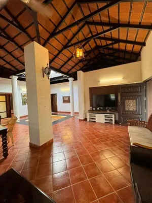 a living room with a tiled floor and a television at Chettinadu Pool Villa in Pollāchi