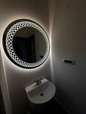 a bathroom with a round mirror above a sink at Chettinadu Pool Villa in Pollāchi