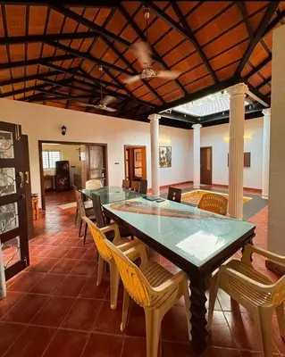 a dining room with a glass table and chairs at Chettinadu Pool Villa in Pollāchi