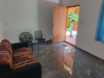 a living room with a couch and chairs and a door at JK Cottages in Suntikoppa