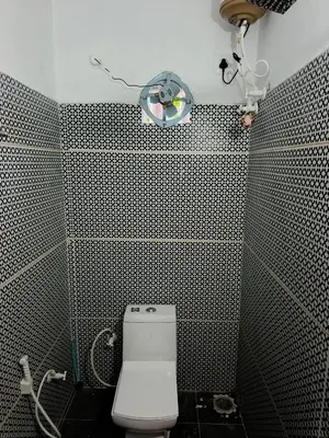 a bathroom with a toilet and a light on the wall at JK Cottages in Suntikoppa