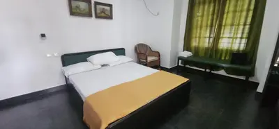 a bedroom with a bed and a chair in it at Kodamukku cottage in Trichūr