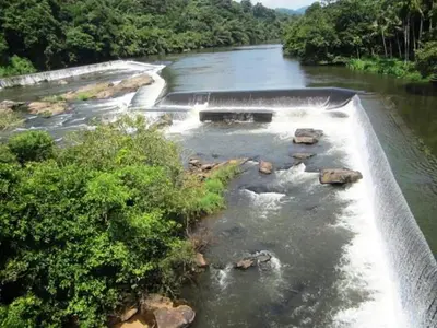 a river with rocks in the water and trees at Jackroot Heritage wood villa Athirappilly in Kallana