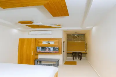 a room with a bed and a table and a desk at MK Residency Calicut near Baby Memorial Hospital in Kozhikode