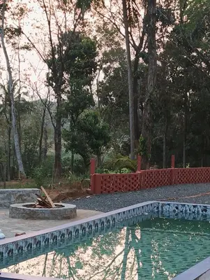 a swimming pool in front of a yard with trees at The Cool Cottage at gaya3farms in Palakkad