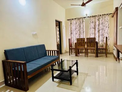 a living room with a blue couch and a table at Anandha Vibes in Guruvāyūr