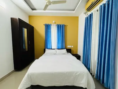 a bedroom with a bed with blue curtains at Anandha Vibes in Guruvāyūr