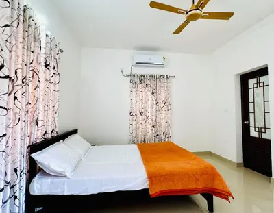 a bedroom with a bed and a ceiling fan at Anandha Vibes in Guruvāyūr